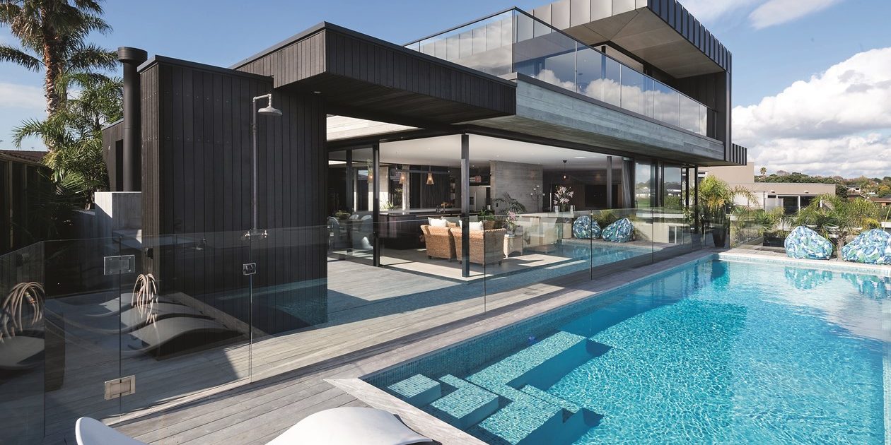 A picture of a concrete pool and a beautiful home