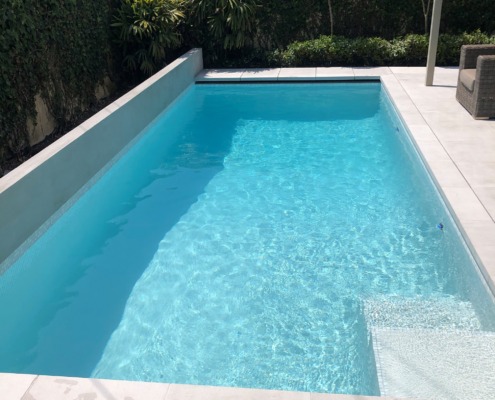 Finished concrete swimming pool with white tiles surrounding